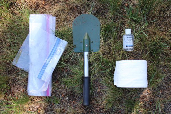 Plastic bags, small shovel, hand sanditizer bottle, and toilet paper make up a kit for outdoor pooping.
