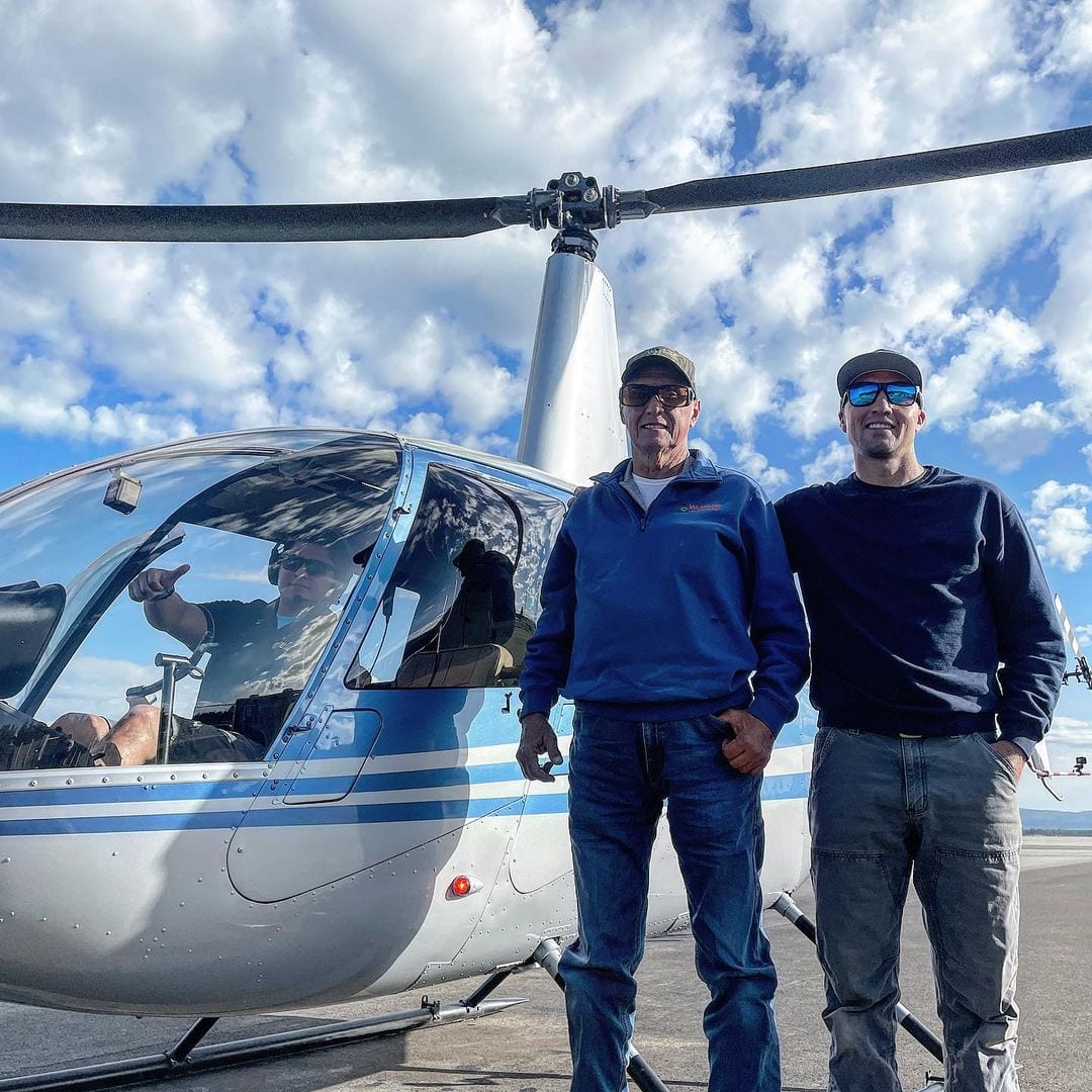 Two men outside a helicopter operated by Yellowstone Helicopters in West Yellowstone, Montana